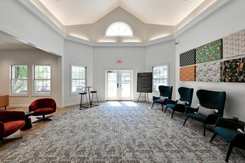 A room with a carpeted floor and a mix of red and black chairs.